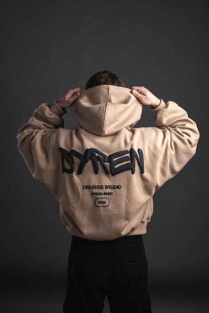 SYREN 1.0 hoodie back shot – model putting on hood, puff print logo visible
