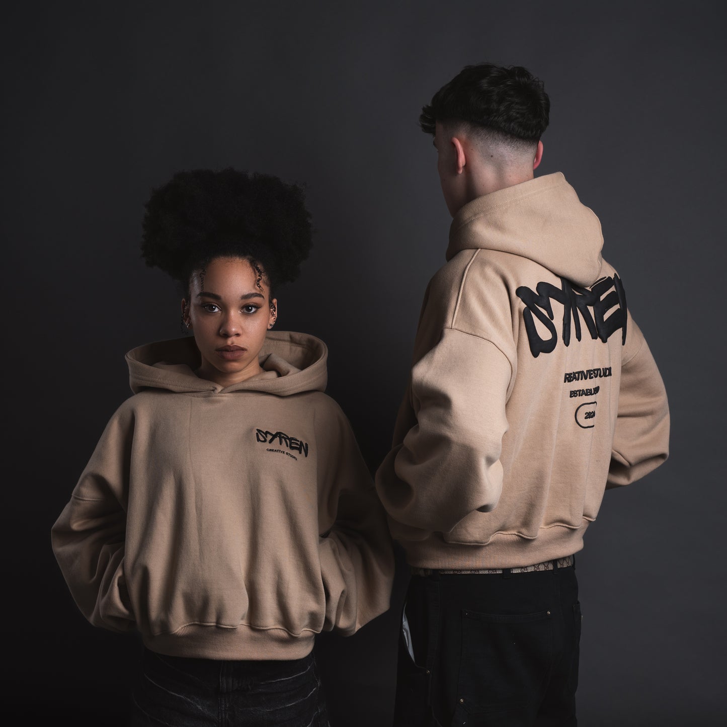 Back view of two models in SYREN hoodie showing sewed logo and puff print logo